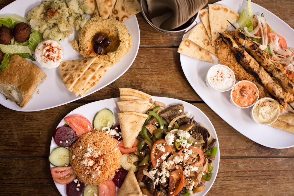 Tradycyjne greckie dania na stole: souvlaki, sałatka horiatiki z fetą i oliwkami, grillowane ryby oraz dodatki w postaci pity, warzyw i sosów