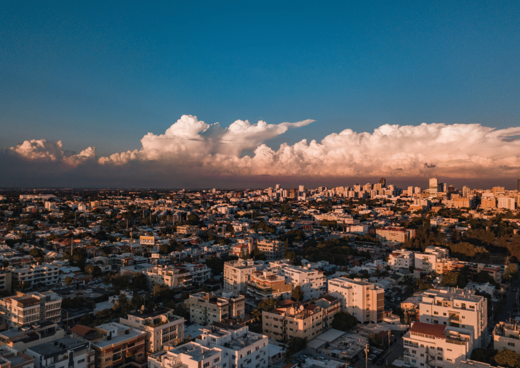 Panorama miasta Santo Domingo o zachodzie słońca, z gęstą zabudową i wieżowcami w oddali.