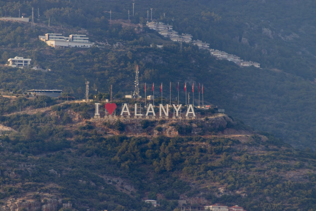 Napis "I love Alanya" na górze wśród zielonych drzew.