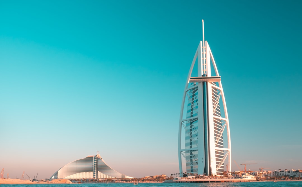 Ikoniczny hotel Burj Al Arab w Dubaju z widokiem na morze i błękitne niebo.
