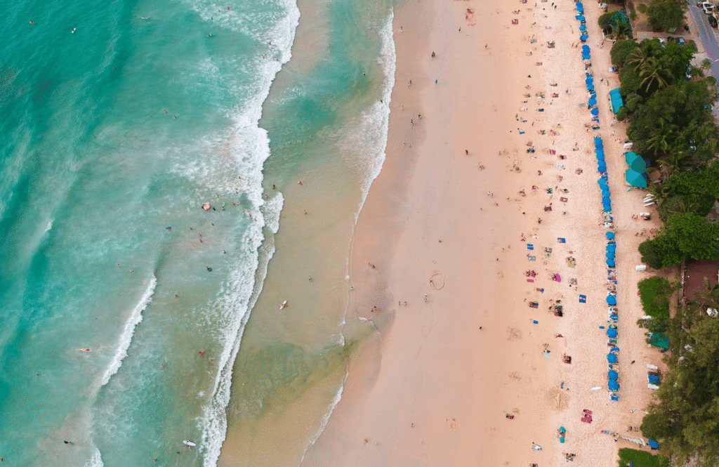 Widok z lotu ptaka na Karon Beach z równym rzędem parasoli i turkusową wodą, Phuket, Tajlandia