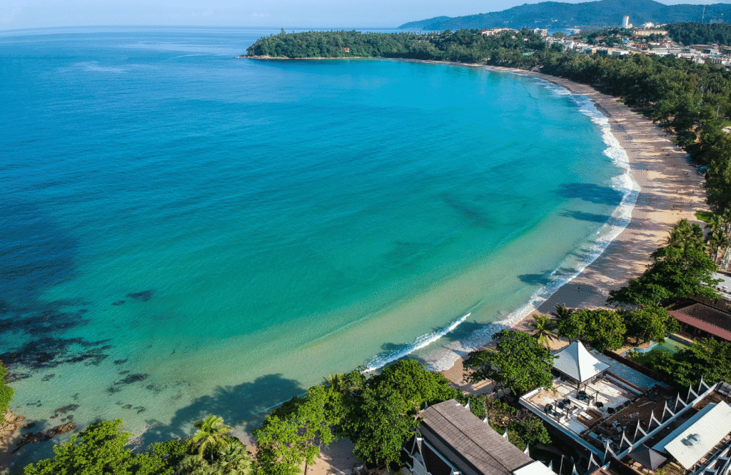 Zielona zatoka i łagodna linia brzegowa Kata Beach otoczona roślinnością i hotelami, Phuket, Tajlandia