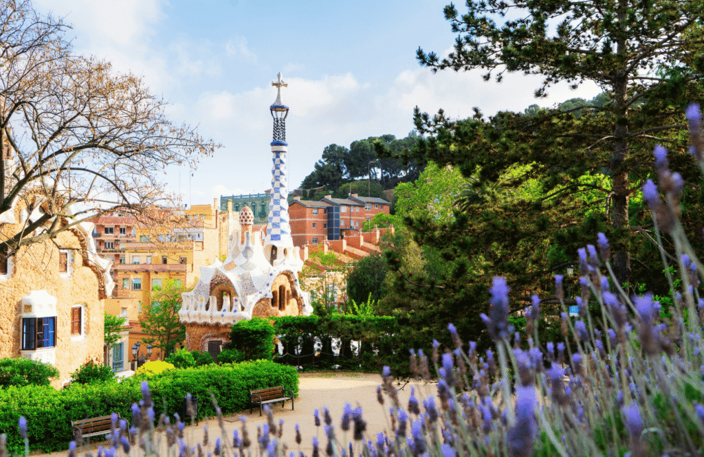 Kolorowe kwiaty lawendy i architektura Parku Güell z krzyżem widocznym na wzgórzu, Barcelona