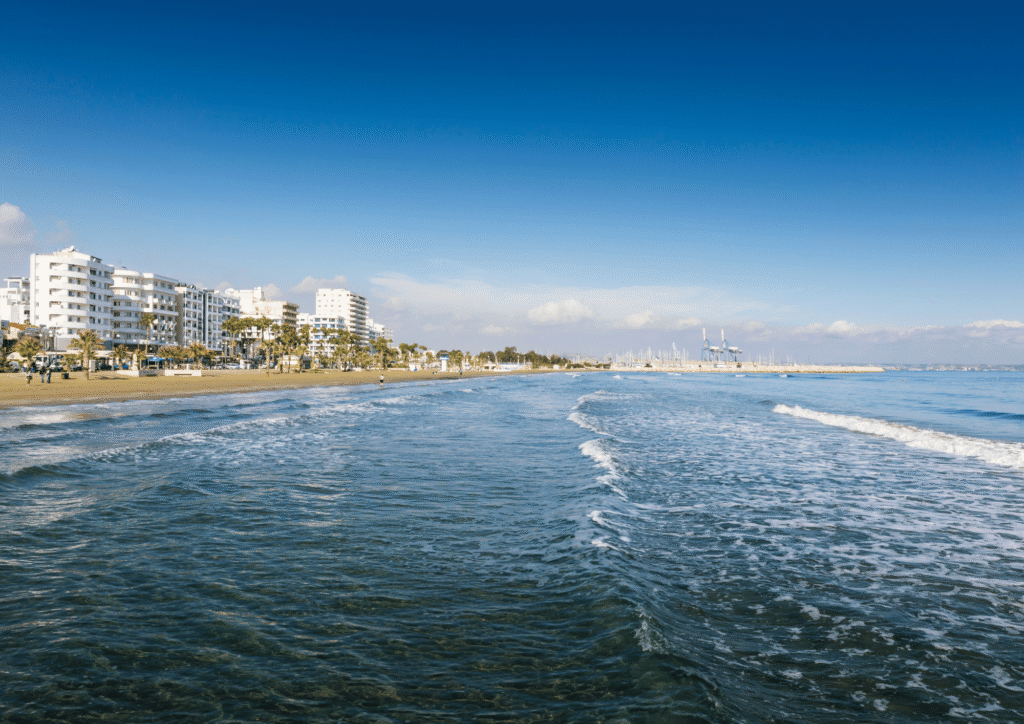 Plaża Finikoudes z błękitnym morzem i deptakiem z palmami, Larnaka, Cypr