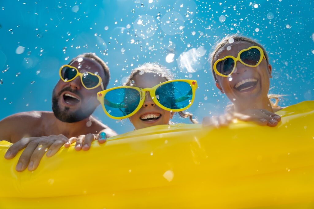 Uśmiechnięta rodzina w kolorowych okularach bawi się w wodzie podczas wakacji all inclusive z Coral Family Club