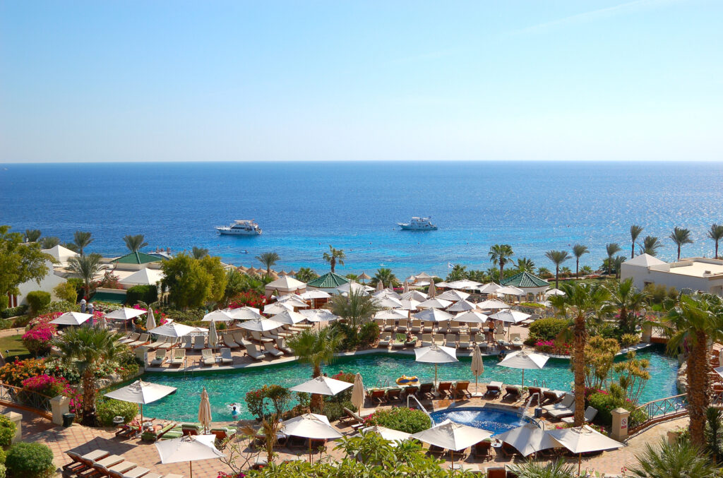 Basen hotelowy z widokiem na Morze Czerwone w Sharm el Sheikh. Luksusowy resort w otoczeniu palm. Idealne miejsce na Egipt All Inclusive.
