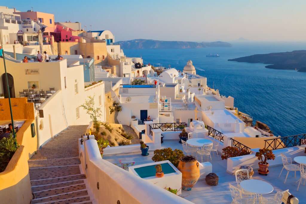 Białe domy z niebieskimi kopułami na skarpie nad lazurowym morzem, charakterystyczny widok na Santorini