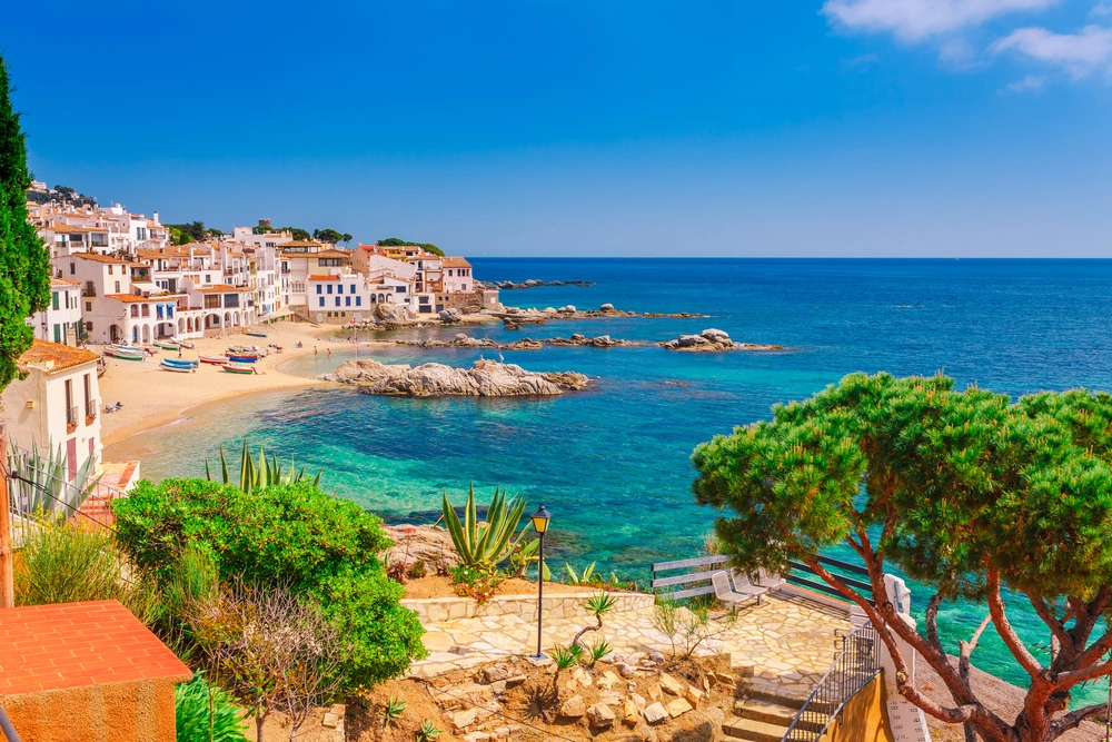 Malownicza zatoka Costa Brava z białymi domami, plażą i turkusowym morzem – widok idealny na wakacje w Hiszpanii.