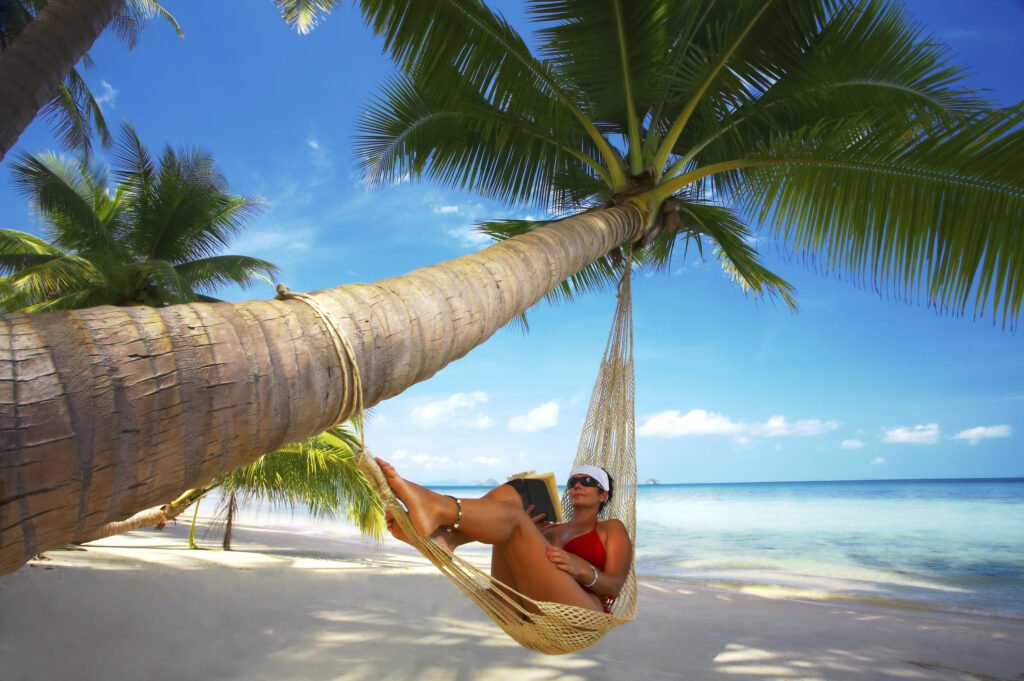 Kobieta relaksująca się w hamaku zawieszonym między palmami nad białą, piaszczystą plażą na Malediwach