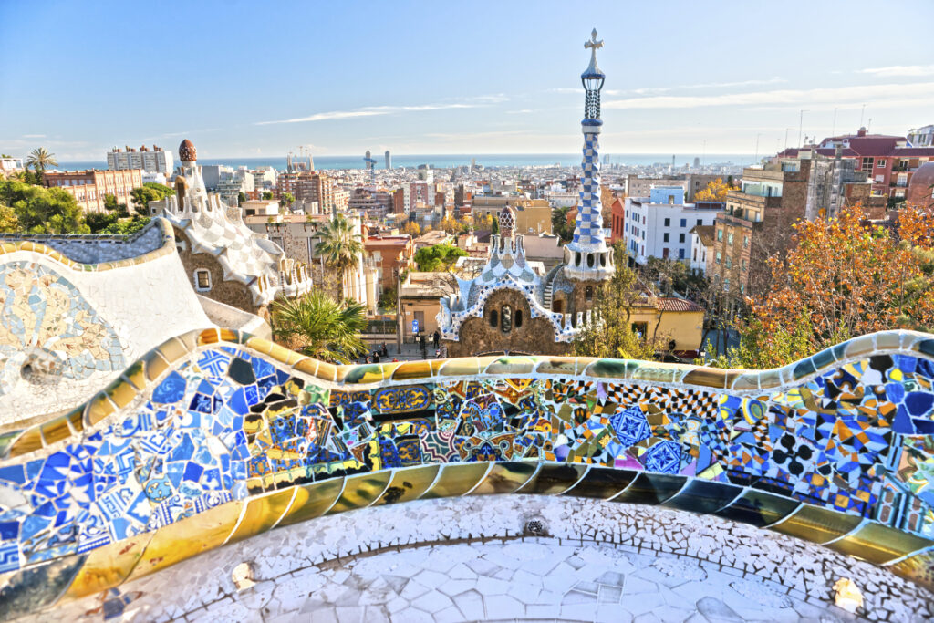Widok na kolorowe mozaiki i turystyczną panoramę Barcelony z tarasu Parku Güell autorstwa Antonio Gaudíego.
