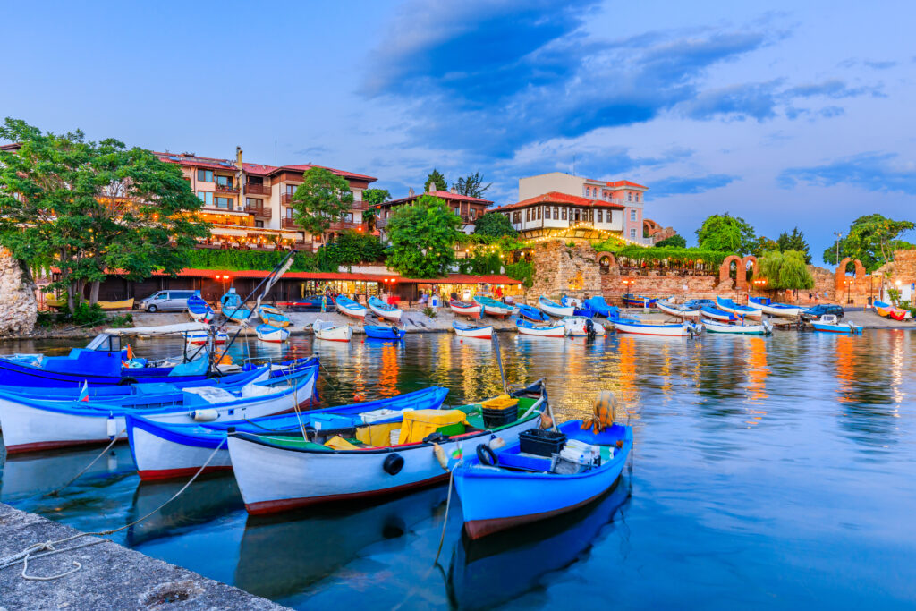 Malowniczy port rybacki w Nesebyrze, Bułgaria All Inclusive – kolorowe łodzie i urokliwe budynki nad Morzem Czarnym o zmierzchu.