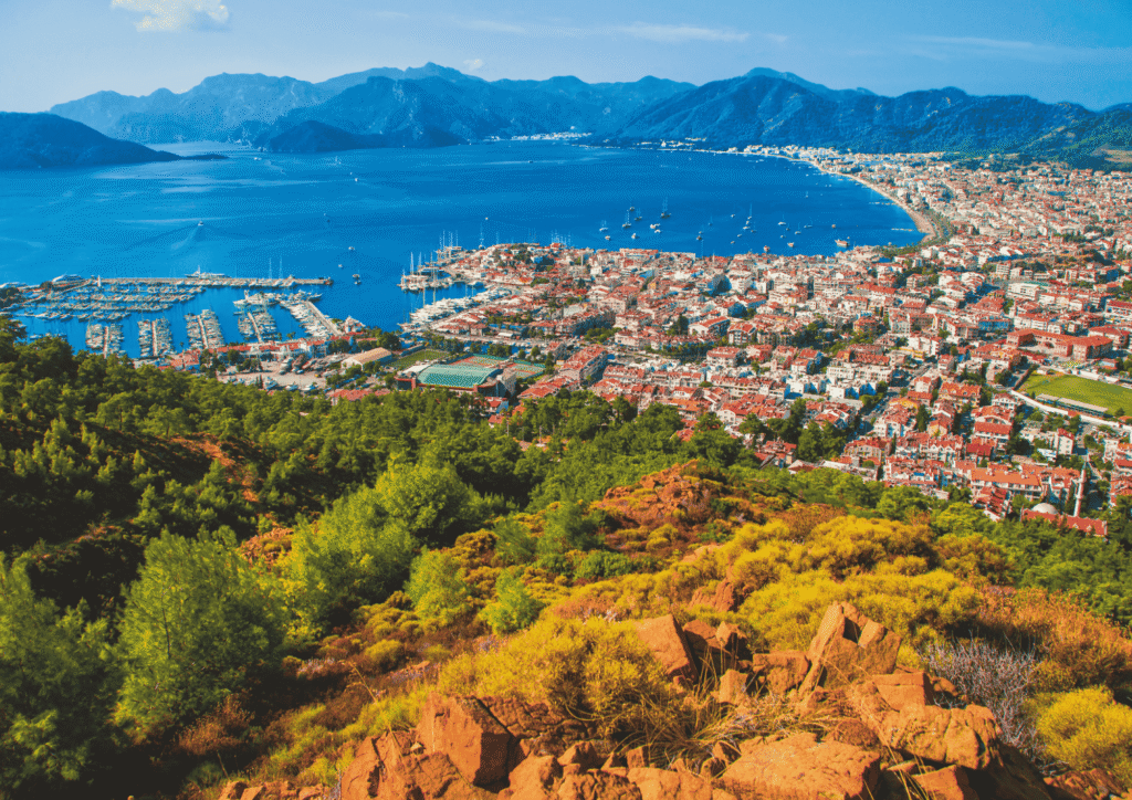 Panorama Marmaris na tureckim wybrzeżu Egejskim z mariną pełną jachtów, zatoką otoczoną górami i zabudową miasta widzianą z punktu widokowego na wzgórzu