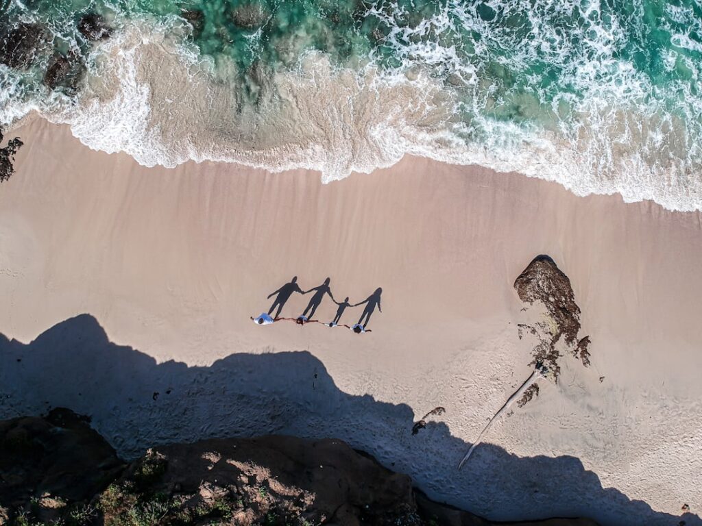 Rodzina z dziećmi spaceruje po piaszczystej plaży podczas ferii zimowych w tropikach.