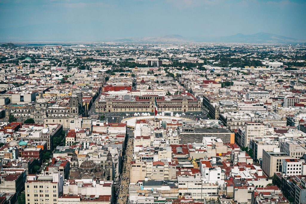 Flaga Meksyku powiewająca nad panoramą Mexico City z górami w tle