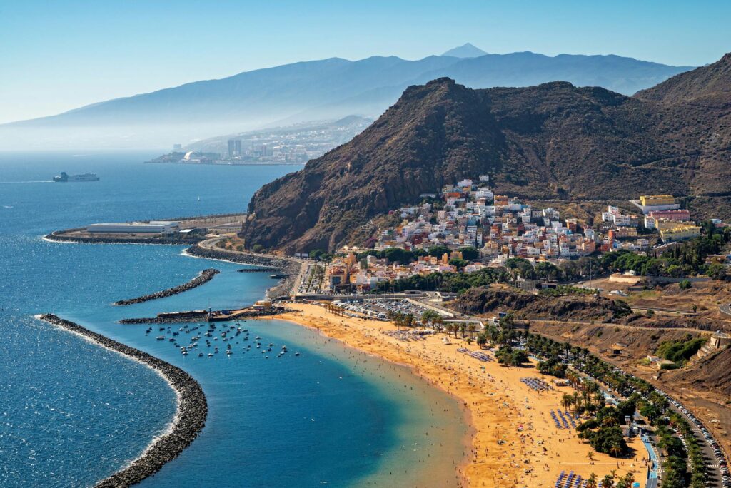 Słoneczna plaża Costa Adeje na jednej z Wysp Kanaryjskich – Teneryfie, z turkusowym oceanem i turystami