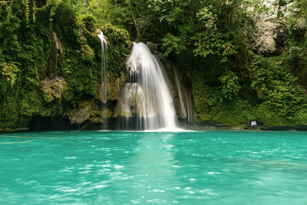 Turysta stojący przy wodospadzie Kawasan na wyspie Cebu, Filipiny