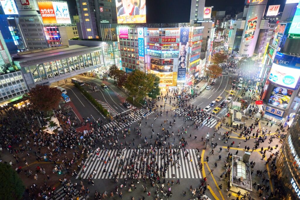 Słynne skrzyżowanie Shibuya Crossing w Tokio o zmierzchu, otoczone wieżowcami i kolorowymi neonami