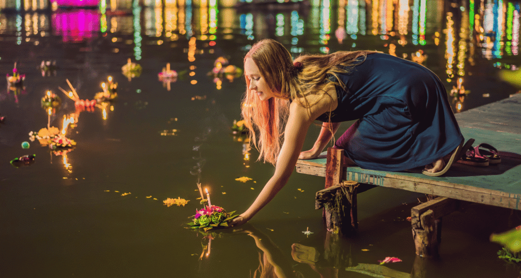 Tajlandia – kobieta puszcza lampion na wodzie podczas święta Loy Krathong.
