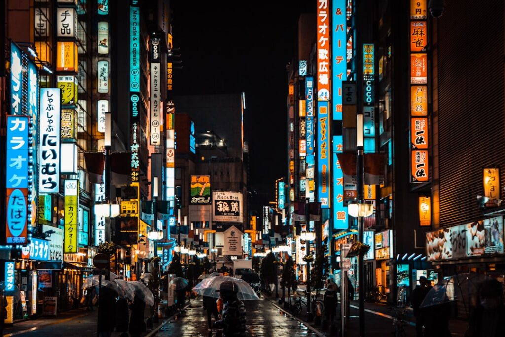 Ulica w dzielnicy Shinjuku w Tokio nocą, z kolorowymi neonami i tłumem ludzi