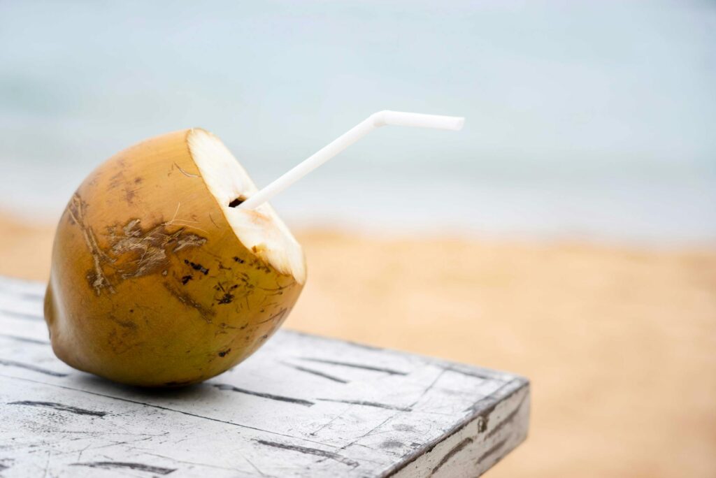 Kokosowy drink z kwiatem na tle karaibskiej plaży
