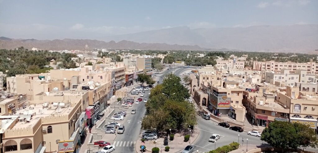 Panorama miasta Nizwa w Omanie z tradycyjną zabudową i palmami na tle gór