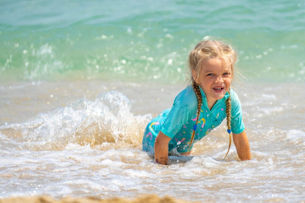 Małe dziecko w różowym dmuchanym kole w kształcie kraba pływa w basenie