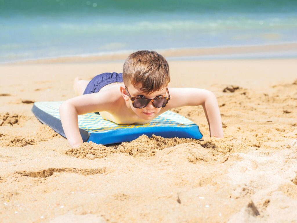 Dziewczynka siedzi na plaży z kawałkiem arbuza w kształcie serca i patrzy w stronę morza