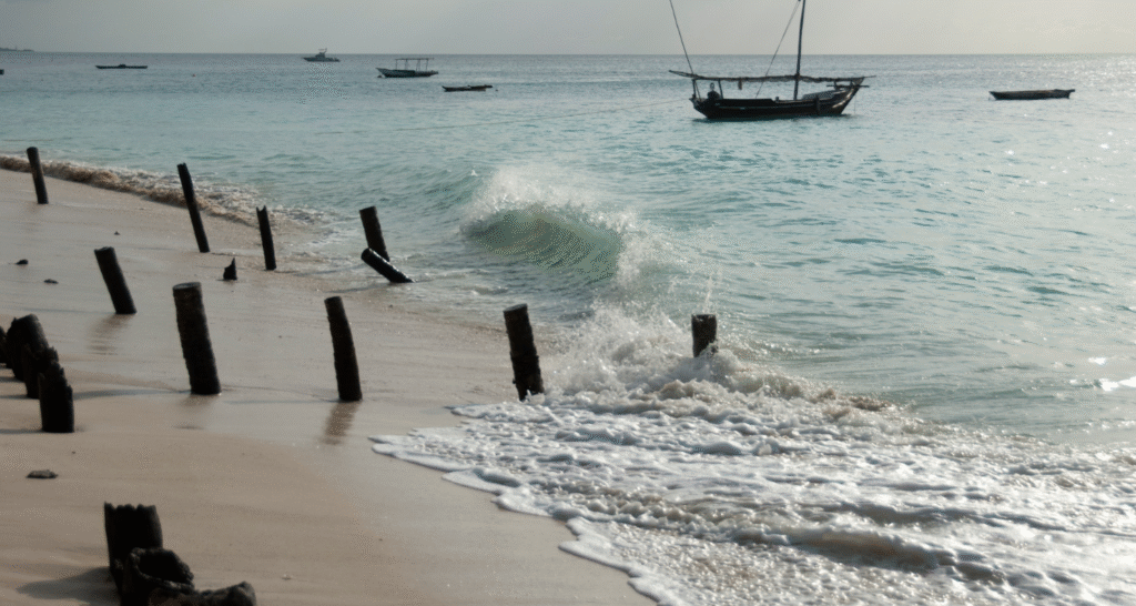 Plaża Nungwi na Zanzibarze z tradycyjnymi łodziami dhow i falami rozbijającymi się o brzeg