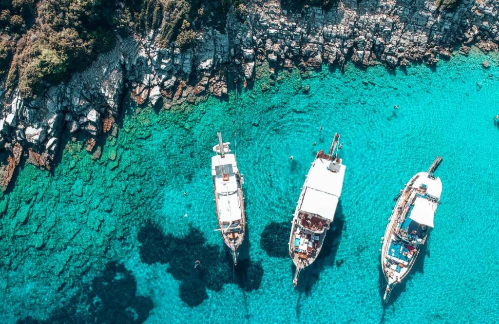 Lazurowa woda i łodzie przy skalistym wybrzeżu Bodrum – Turcja na spontaniczne wakacje all inclusive