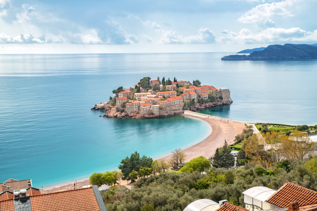 Sveti Stefan w Czarnogórze widziany z góry – wyspa połączona z lądem wąską plażą i otoczona turkusowym morzem