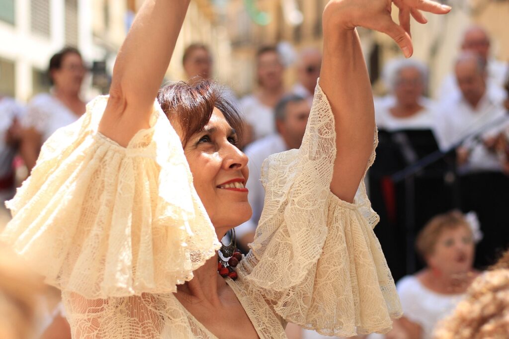 Grupa tancerzy flamenco wykonujących układ na hiszpańskim placu w eleganckich tradycyjnych strojach.
