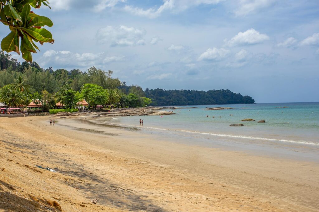 Tropikalna plaża z palmami i łodziami na tle błękitnego morza w Khao Lak