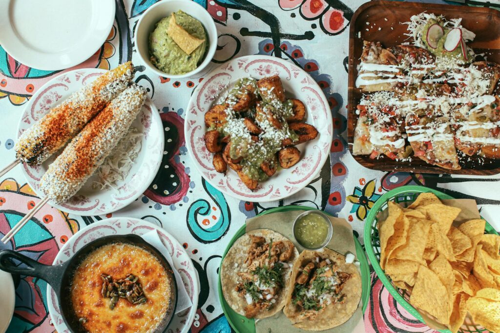 Zestaw najpopularniejszych dań kuchni meksykańskiej, takich jak nachos, tacos i burrito, podanych z warzywami i salsą