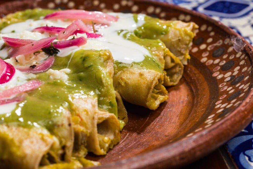 Tradycyjne meksykańskie dodatki i salsa verde w kamiennym moździerzu na kolorowym stole