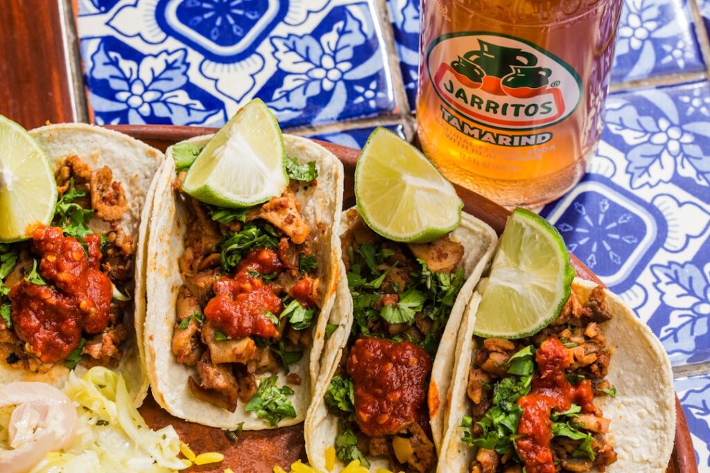 Tacos z mięsem, pomidorami, kolendrą i guacamole podawane na drewnianej desce