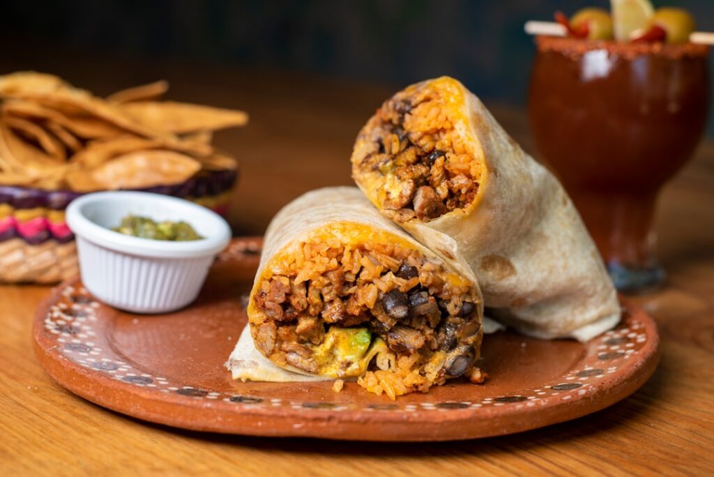 Burrito wypełnione mięsem, warzywami i śmietaną, podane na drewnianej desce