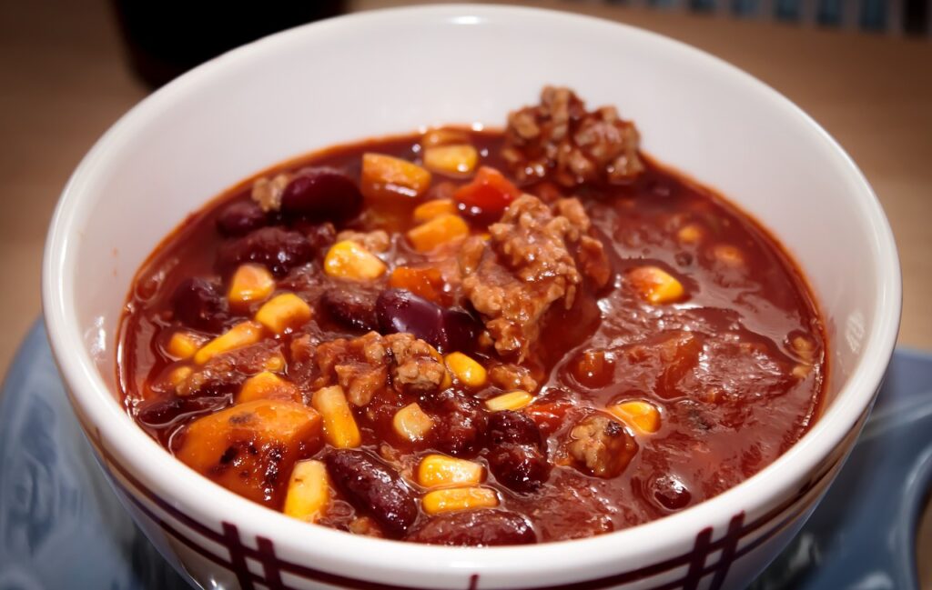 Chili con carne z fasolą, mięsem i warzywami podane w misce z dodatkiem natki pietruszki