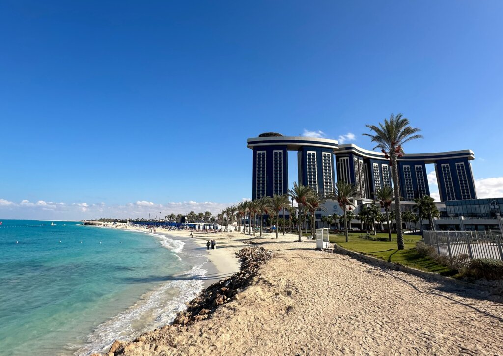 Piaszczysta plaża i luksusowy hotel Rixos Premium Alamein nad turkusowym morzem