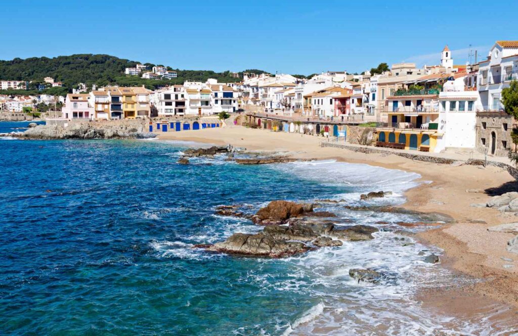 Nadmorska trasa biegowa wzdłuż plaży Calella na Costa Brava – malownicze wybrzeże z kolorowymi domami i lazurowym morze