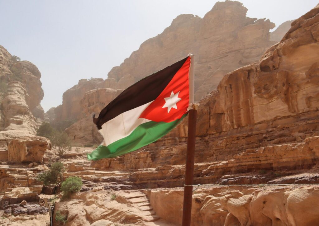 Flaga Jordanii powiewająca na tle skalnych formacji i pustynnego krajobrazu w Azji