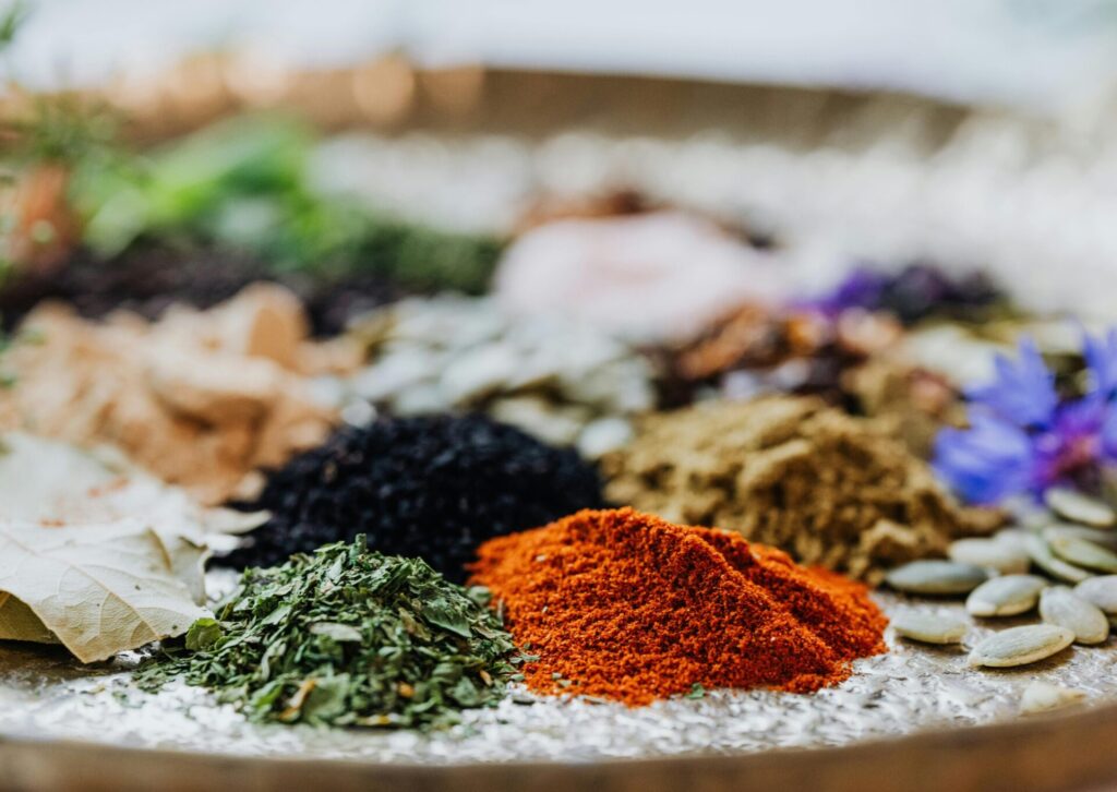 Arabskie przyprawy i suszone zioła w zbliżeniu – papryka, liście laurowe i nasiona na drewnianej tacy