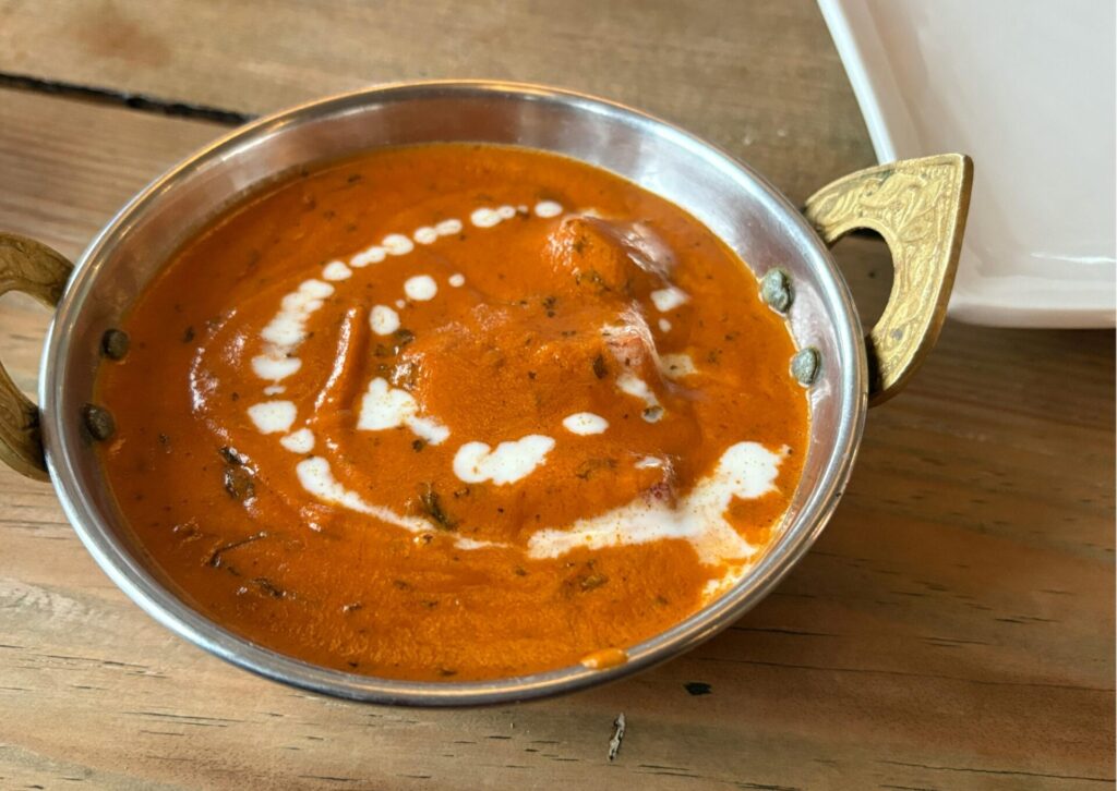 Butter chicken w kremowym sosie pomidorowym podany w metalowej miseczce
