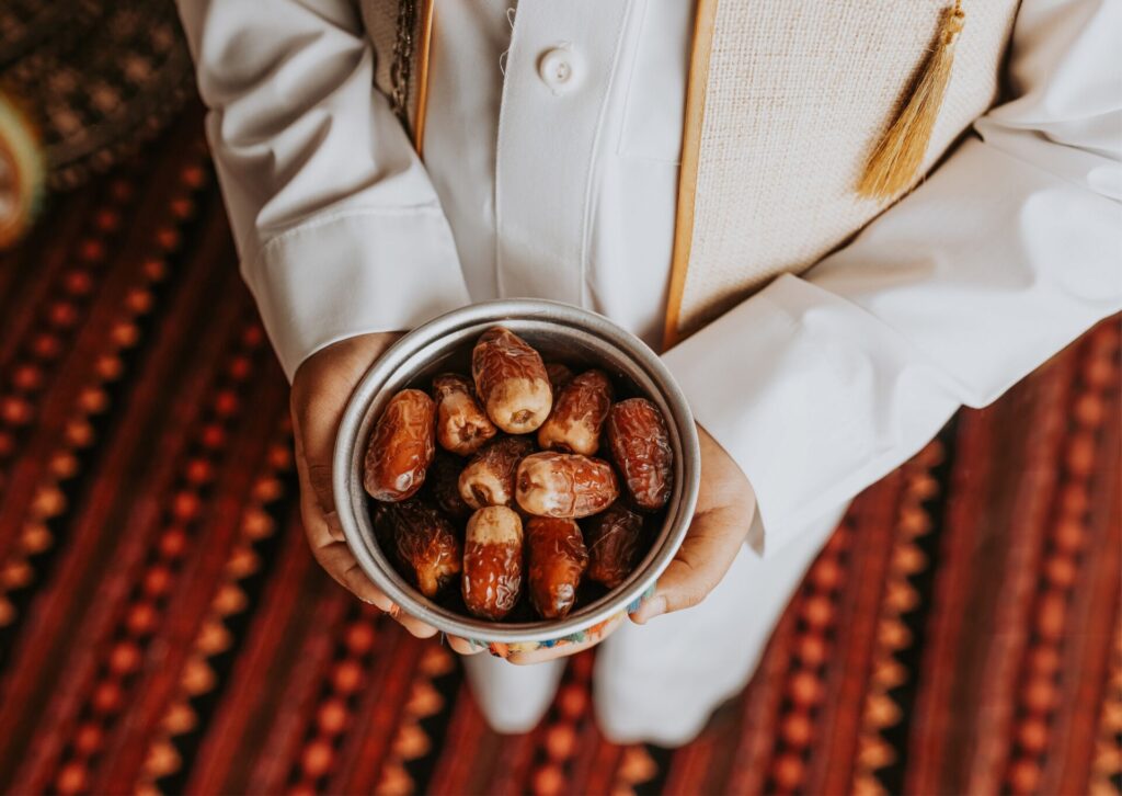 Mężczyzna w tradycyjnym stroju trzyma miskę z daktylami przed iftarem w Egipcie