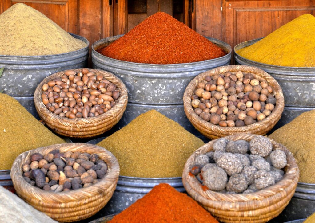 Arabskie przyprawy w metalowych pojemnikach oraz kosze z orzechami na tradycyjnym bazarze