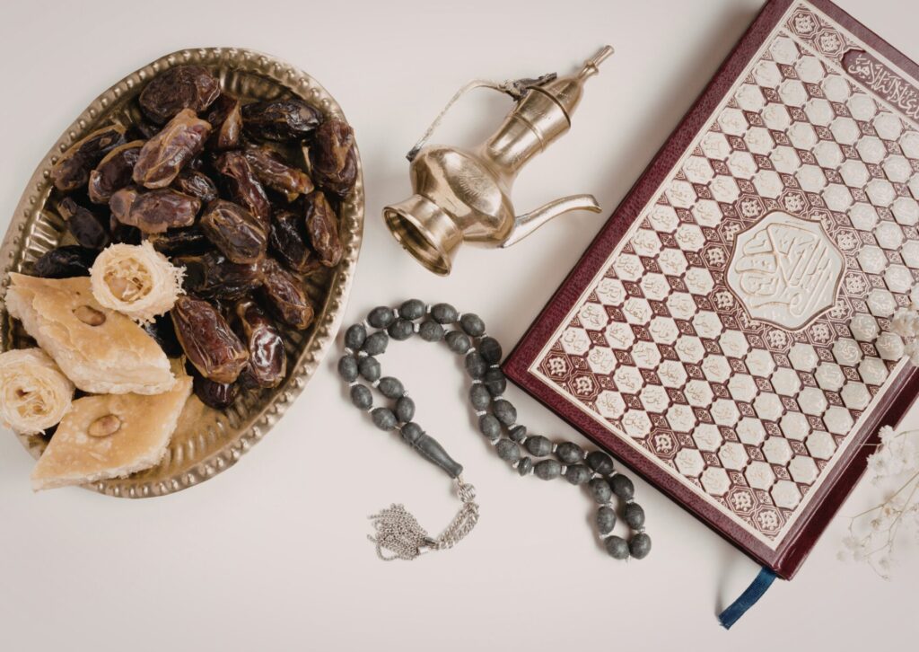 Talerz z daktylami i słodkościami, arabski dzbanek oraz Koran podczas wieczornego iftaru