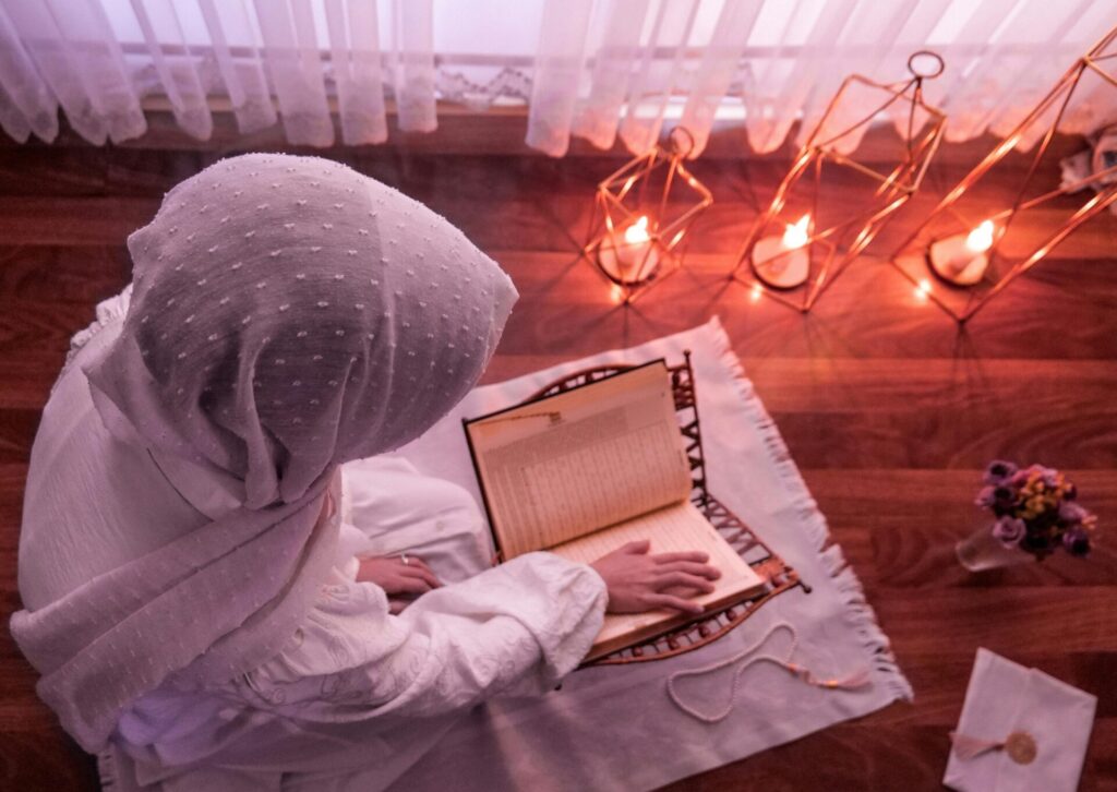Kobieta czytająca Koran przy świecach podczas ramadanu w Turcji