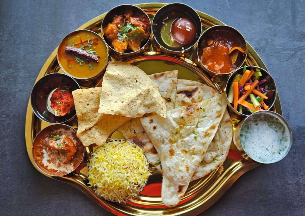 Zestaw tradycyjnych potraw indyjskich z chlebkiem naan, ryżem i różnymi sosami curry