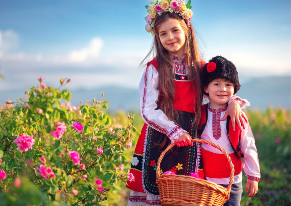 Dzieci w tradycyjnych bułgarskich strojach ludowych na tle kwitnących róż