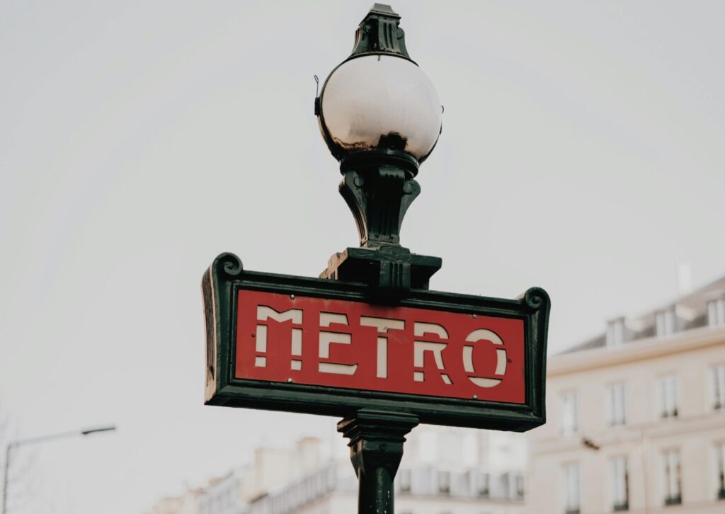 Zabytkowy znak metra w Paryżu na tle paryskiej architektury