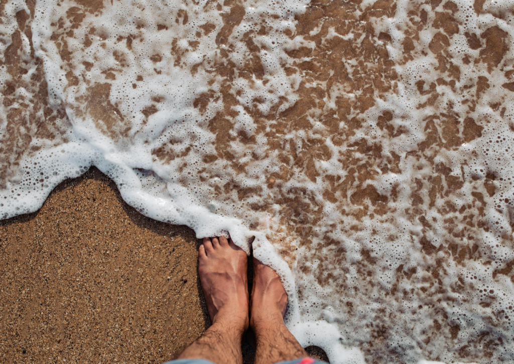 Stopy na piaszczystej plaży obmywane falami morza w Hiszpanii